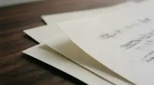 A fan of printed document pages overlapping on a dark desk in raking light